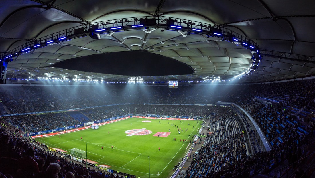 Stadion olahraga besar dengan lampu sorot menyala sebelum pertandingan